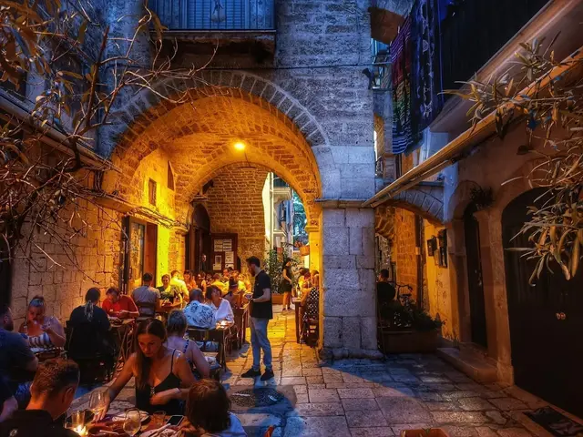 I tavoli del ristorante sotto l'arco illuminato di un vicolo di Bari vecchia